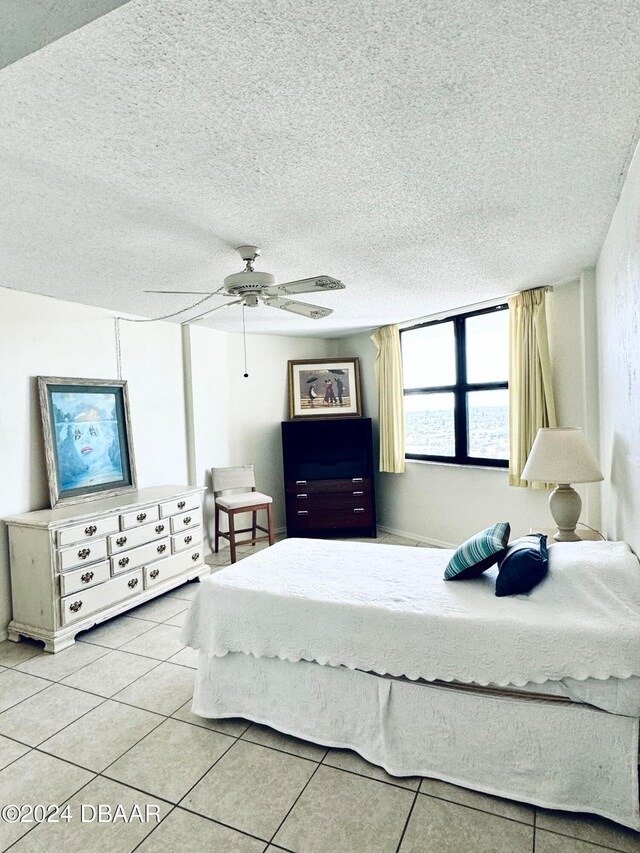 tiled bedroom featuring ceiling fan and a textured ceiling