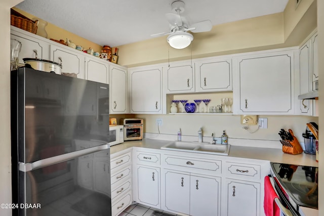 kitchen featuring black refrigerator, sink, and white cabinets