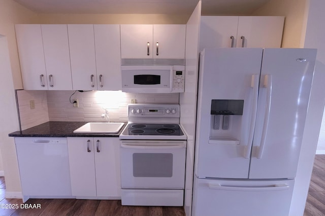 kitchen with white appliances, white cabinetry, dark stone countertops, sink, and dark hardwood / wood-style floors