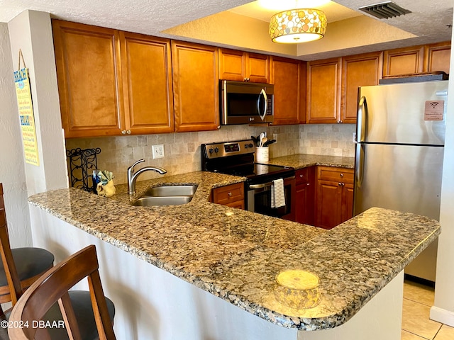 kitchen featuring stainless steel appliances, a kitchen bar, sink, and kitchen peninsula