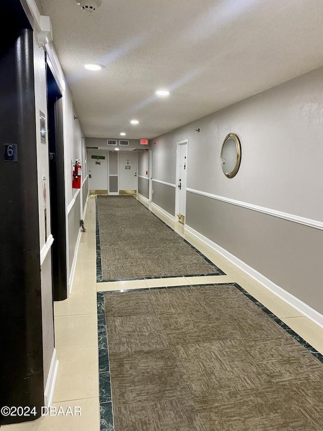 2615 S Atlantic Ave Unit 6G, Daytona Beach Shores, FL 32118 - hall featuring inlaid floor details, recessed lighting, baseboards, a textured ceiling, and tile patterned flooring