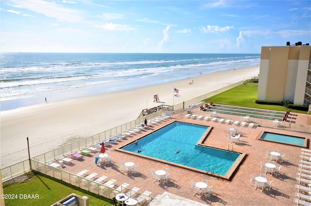 view of pool featuring a patio, a water view, and a beach view