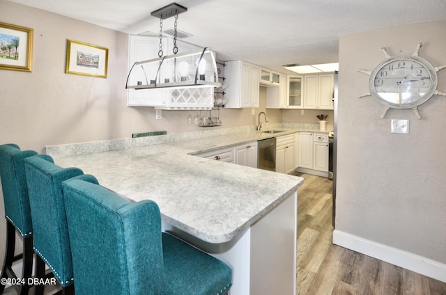 kitchen with white cabinetry, a breakfast bar, kitchen peninsula, pendant lighting, and light wood-type flooring