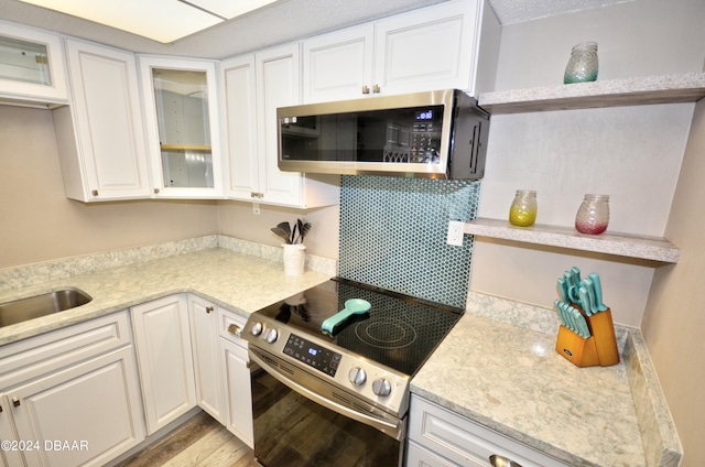 kitchen with white cabinetry, appliances with stainless steel finishes, light hardwood / wood-style floors, and light stone counters