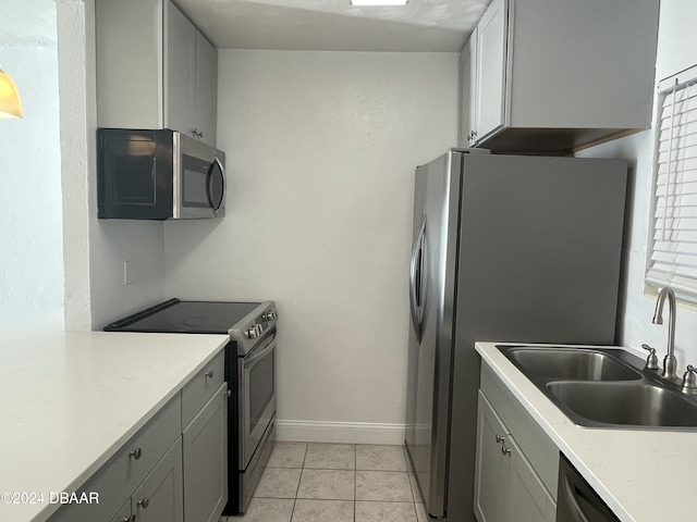 kitchen featuring gray cabinetry, sink, light tile patterned floors, and stainless steel appliances