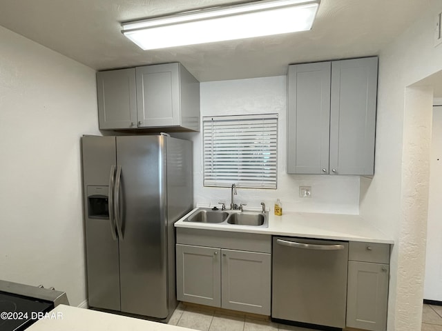 kitchen with sink, light tile patterned floors, gray cabinets, and appliances with stainless steel finishes