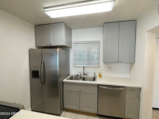 kitchen featuring light tile patterned floors, appliances with stainless steel finishes, sink, and gray cabinetry