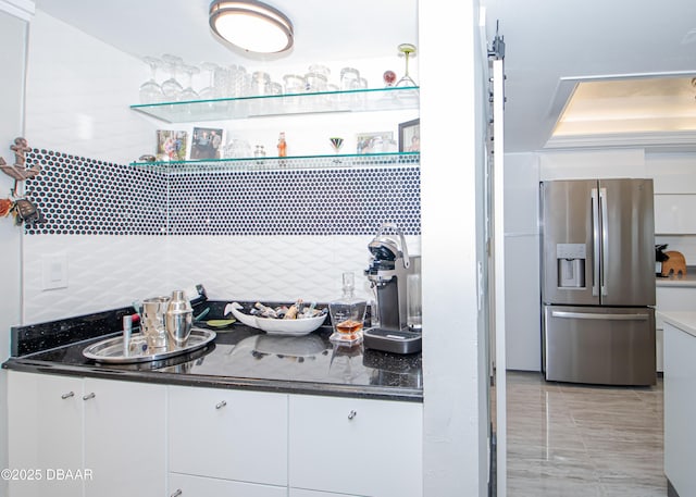 kitchen featuring stainless steel fridge, tasteful backsplash, dark stone countertops, white cabinets, and light tile patterned flooring