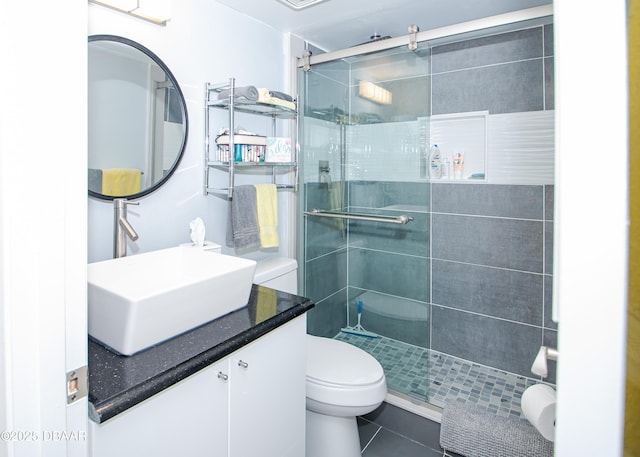 bathroom featuring toilet, vanity, tile patterned floors, and a shower with shower door