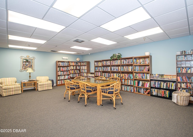 carpeted dining space featuring a paneled ceiling