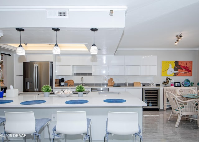 kitchen with beverage cooler, stainless steel fridge with ice dispenser, hanging light fixtures, white cabinets, and tasteful backsplash