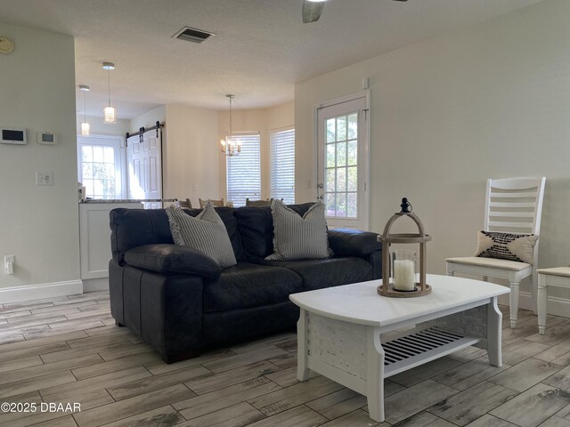 living room featuring a textured ceiling, light wood-type flooring, ceiling fan, and a barn door