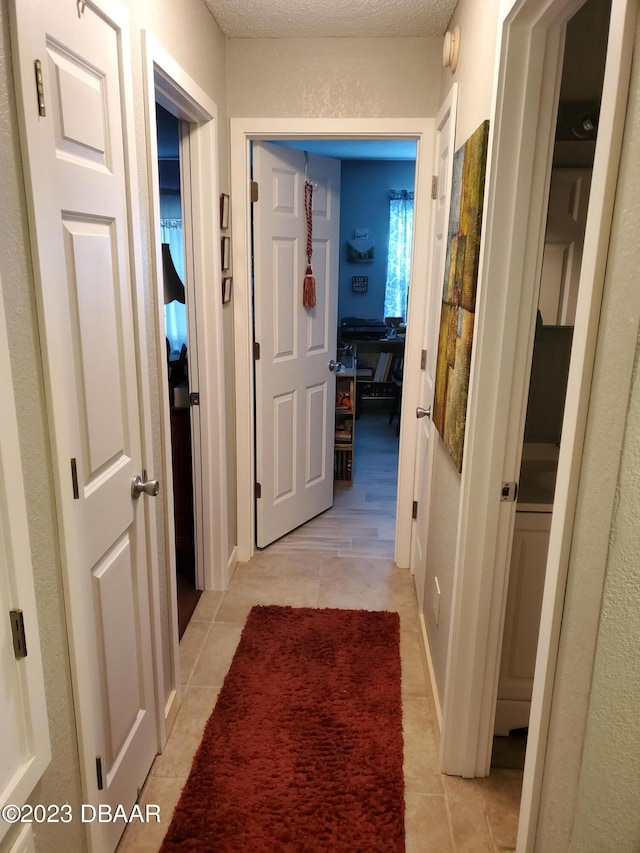 hall featuring a textured ceiling and light tile patterned floors