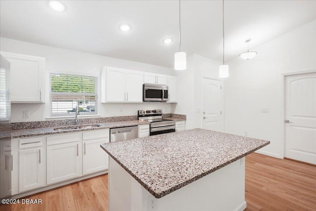 kitchen with sink, a kitchen island, white cabinets, and appliances with stainless steel finishes