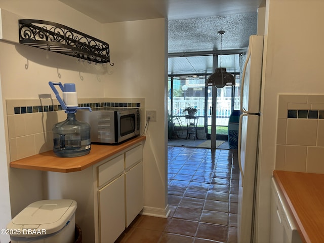 5500 Ocean Shore Blvd Unit 18, Ormond Beach, FL 32176 - kitchen featuring white cabinets, freestanding refrigerator, stainless steel microwave, dark tile patterned flooring, and butcher block countertops