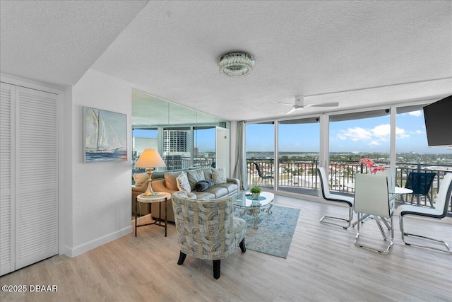 interior space featuring ceiling fan, floor to ceiling windows, light hardwood / wood-style flooring, and a textured ceiling