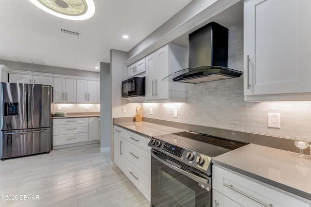 64 Alberta Ave, Ponce Inlet, FL 32127 - kitchen featuring stainless steel appliances, wall chimney range hood, decorative backsplash, white cabinets, and light wood-type flooring