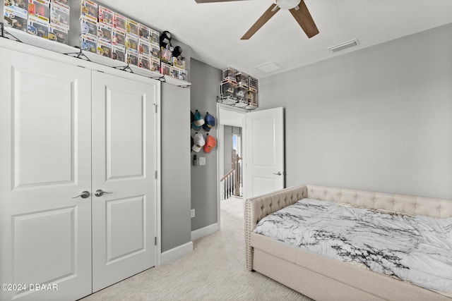 bedroom with ceiling fan, light carpet, and a closet