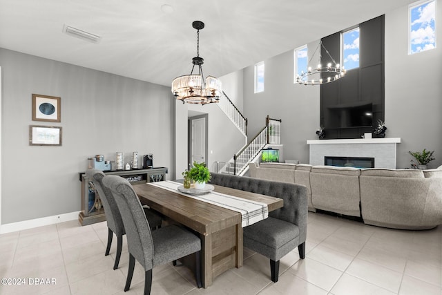137 Azure Mist Way, Daytona Beach, FL 32124 - dining space with a chandelier, a glass covered fireplace, light tile patterned floors, stairs, and a high ceiling