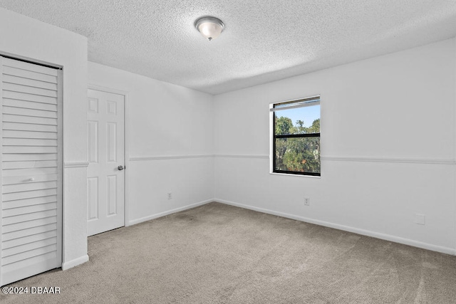 unfurnished bedroom featuring a textured ceiling, a closet, and carpet floors