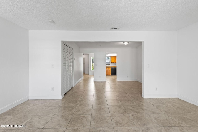 tiled empty room with a textured ceiling