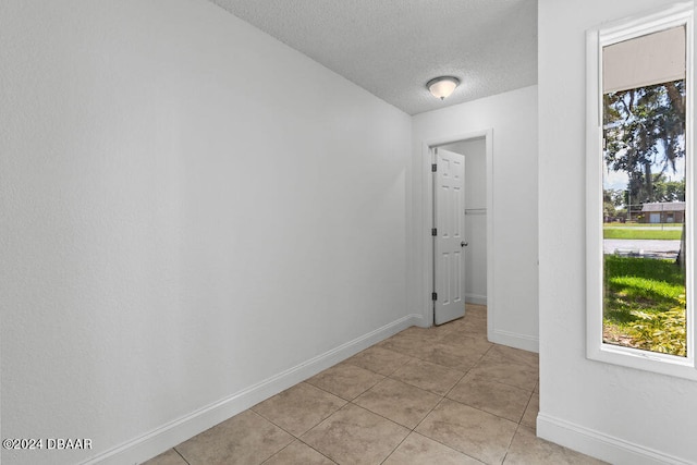 hall with plenty of natural light, light tile patterned floors, and a textured ceiling