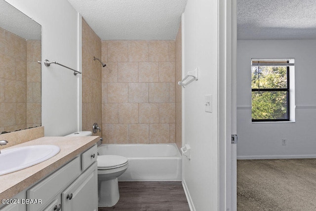 full bathroom with toilet, tiled shower / bath, hardwood / wood-style flooring, a textured ceiling, and vanity