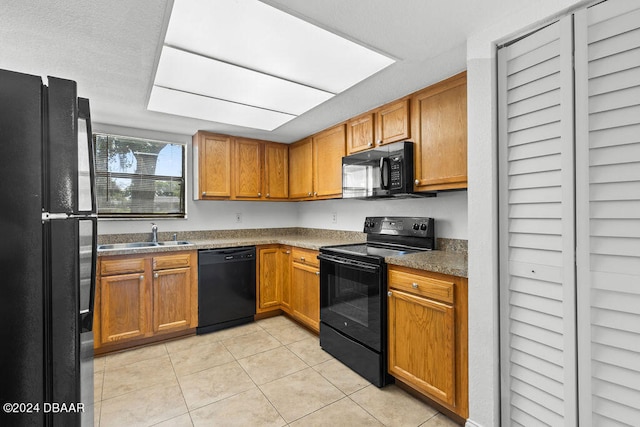 kitchen with light tile patterned floors, a textured ceiling, sink, and black appliances