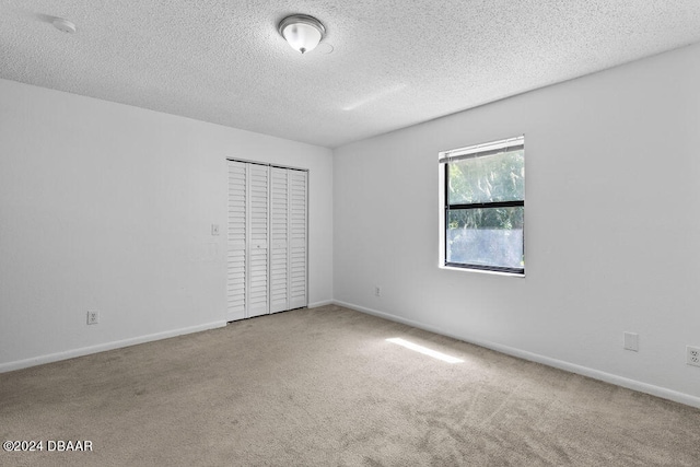 carpeted spare room with a textured ceiling