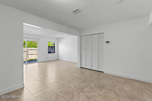 spare room featuring light tile patterned flooring and a textured ceiling