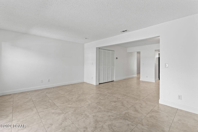 tiled empty room featuring a textured ceiling