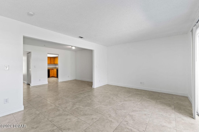 unfurnished room with light tile patterned flooring and a textured ceiling