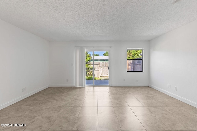 empty room with a textured ceiling and light tile patterned floors