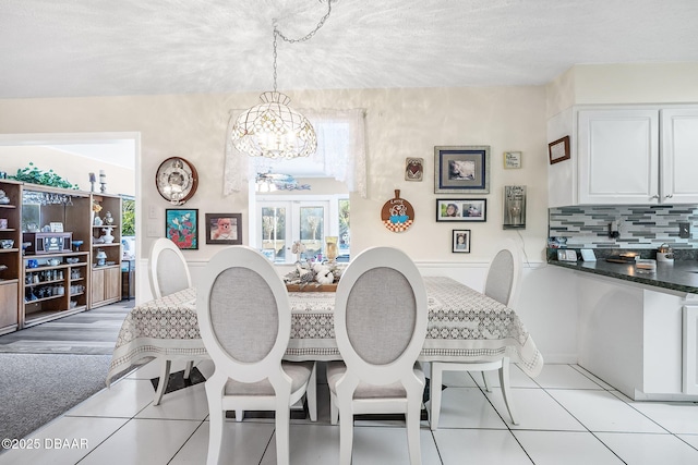 tiled dining room featuring french doors and a notable chandelier