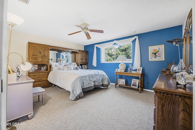 bedroom with ceiling fan, carpet floors, and a textured ceiling