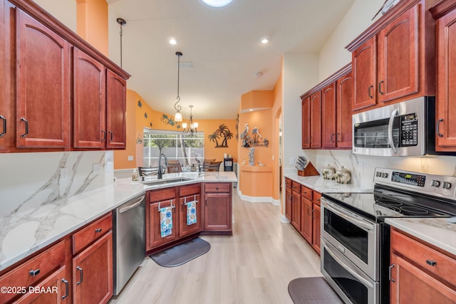 406 Phillips Creek Ln, New Smyrna Beach, FL 32168 - kitchen featuring appliances with stainless steel finishes, light wood-style flooring, hanging light fixtures, a peninsula, and a chandelier