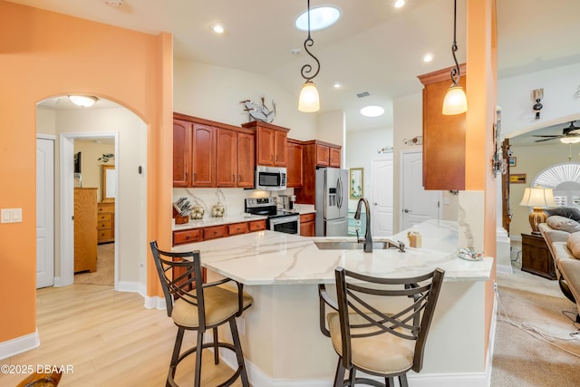 406 Phillips Creek Ln, New Smyrna Beach, FL 32168 - kitchen featuring appliances with stainless steel finishes, a peninsula, light wood-style flooring, light stone countertops, and a breakfast bar