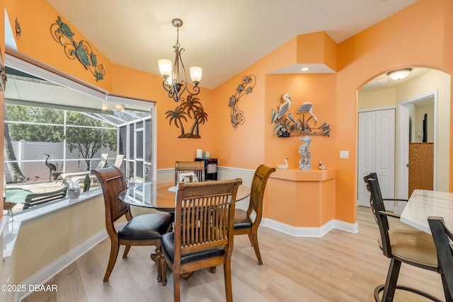 406 Phillips Creek Ln, New Smyrna Beach, FL 32168 - dining area featuring light wood finished floors, arched walkways, vaulted ceiling, and a chandelier