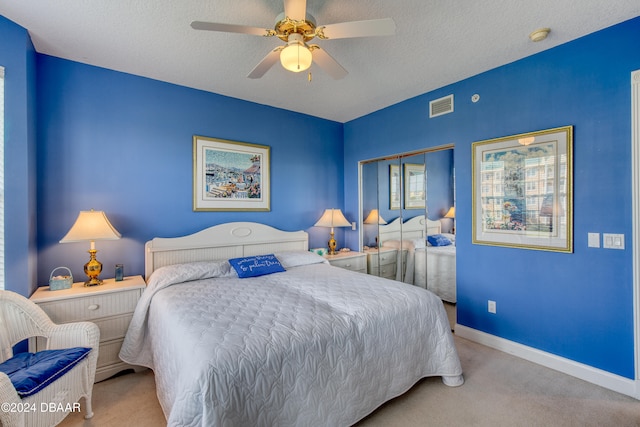 carpeted bedroom with ceiling fan, a closet, and a textured ceiling