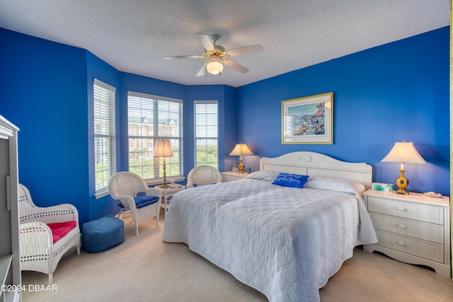 bedroom with ceiling fan, carpet floors, and a textured ceiling