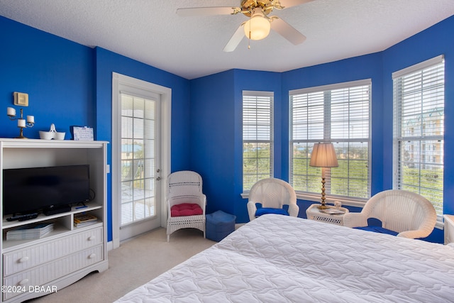 carpeted bedroom featuring access to exterior, a textured ceiling, and ceiling fan