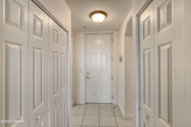 doorway with light tile patterned floors and a textured ceiling