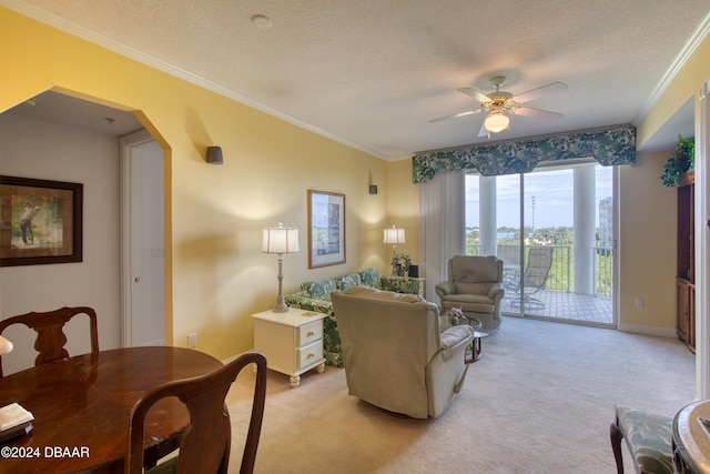 living room featuring ceiling fan, light colored carpet, a textured ceiling, and ornamental molding