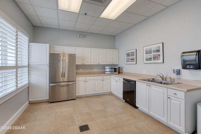 kitchen with white cabinets, appliances with stainless steel finishes, a drop ceiling, and sink