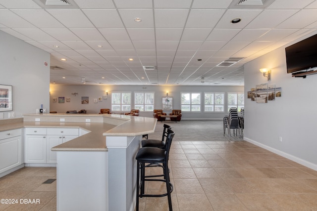 kitchen featuring a kitchen breakfast bar, light tile patterned flooring, a kitchen island, and white cabinetry