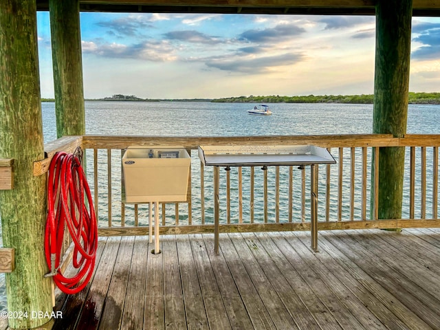 deck at dusk featuring a water view