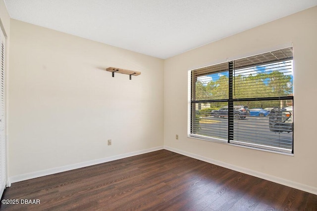 spare room with dark wood finished floors and baseboards