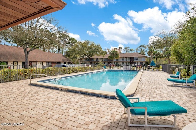 community pool with a residential view, a patio, and fence