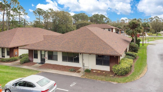 view of front of home featuring a shingled roof and a front lawn