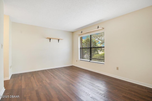 empty room featuring a textured ceiling, wood finished floors, and baseboards